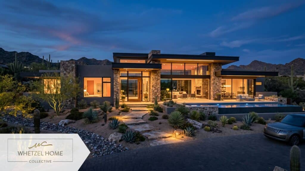 A stunning architectural exterior shot of a brand new, desert-contemporary style house at twilight. The home features a mix of natural stone, sleek stucco, and large geometric windows glowing warmly from the inside. The front yard showcases beautiful, low-water xeriscaping with native desert plants and decorative rocks. Professional real estate dusk photography, luxurious mood.