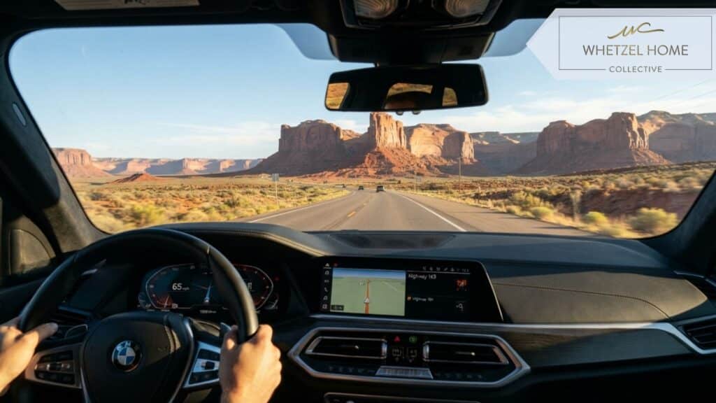 A driver's point of view from inside a modern car looking through the windshield at a clear, open highway, dashboard slightly visible in the foreground, majestic towering red rock canyons ahead, sunny morning commute, photorealistic, cinematic lighting.