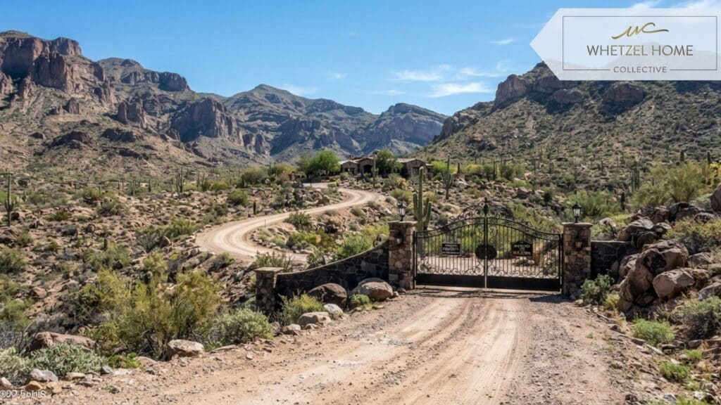 A well-maintained scenic dirt road winding through a mountainous desert region, leading to a sturdy wrought-iron private property gate, flanked by rugged terrain, sunny daylight, crisp and sharp details, realistic style.
