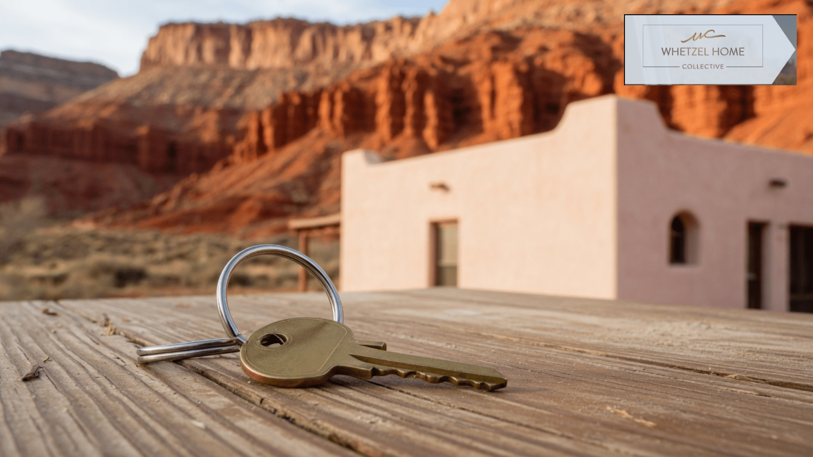 House key on a wood table with a southern Utah home and red cliffs behind