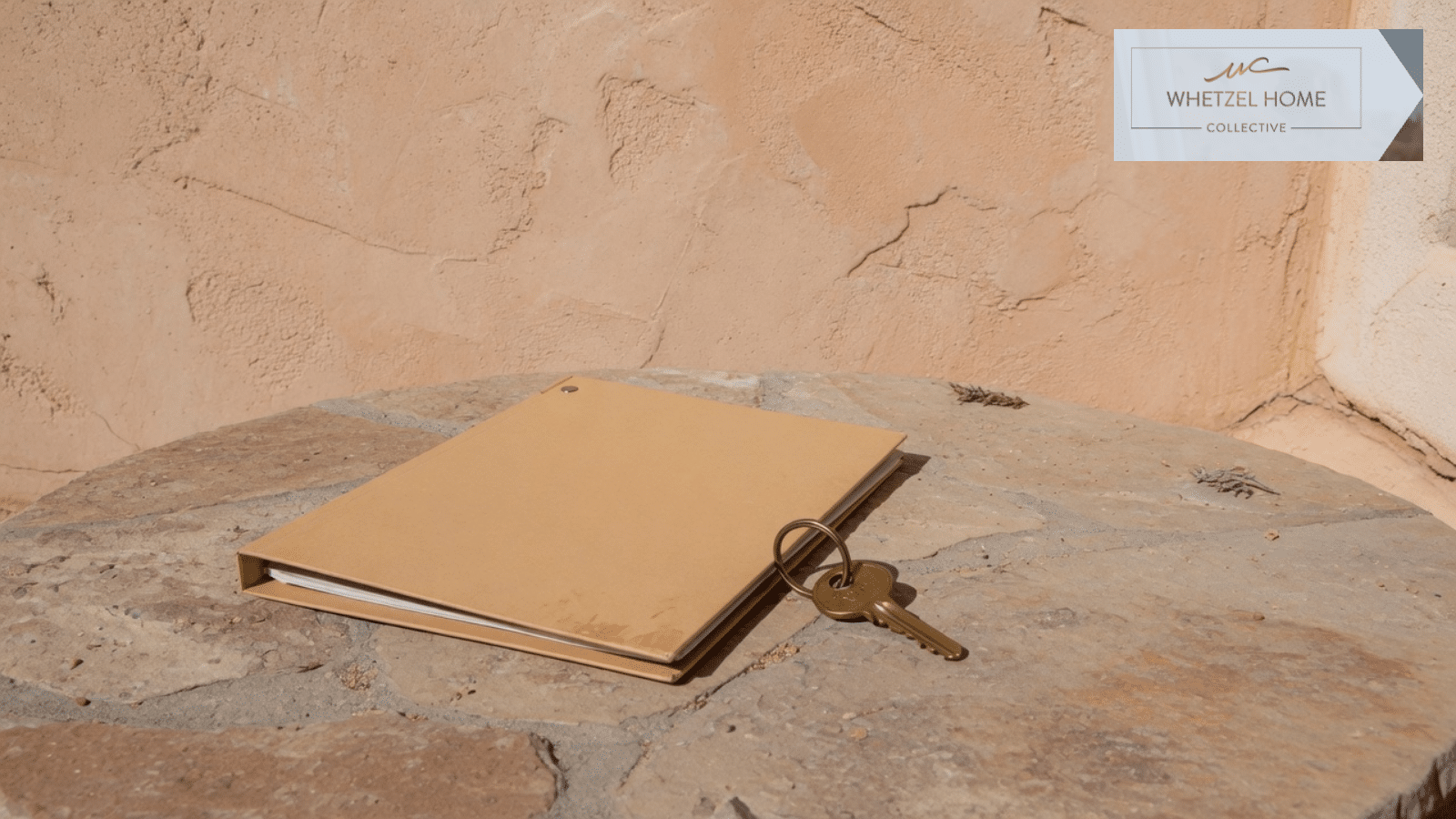 A closed folder and a house key on a counter