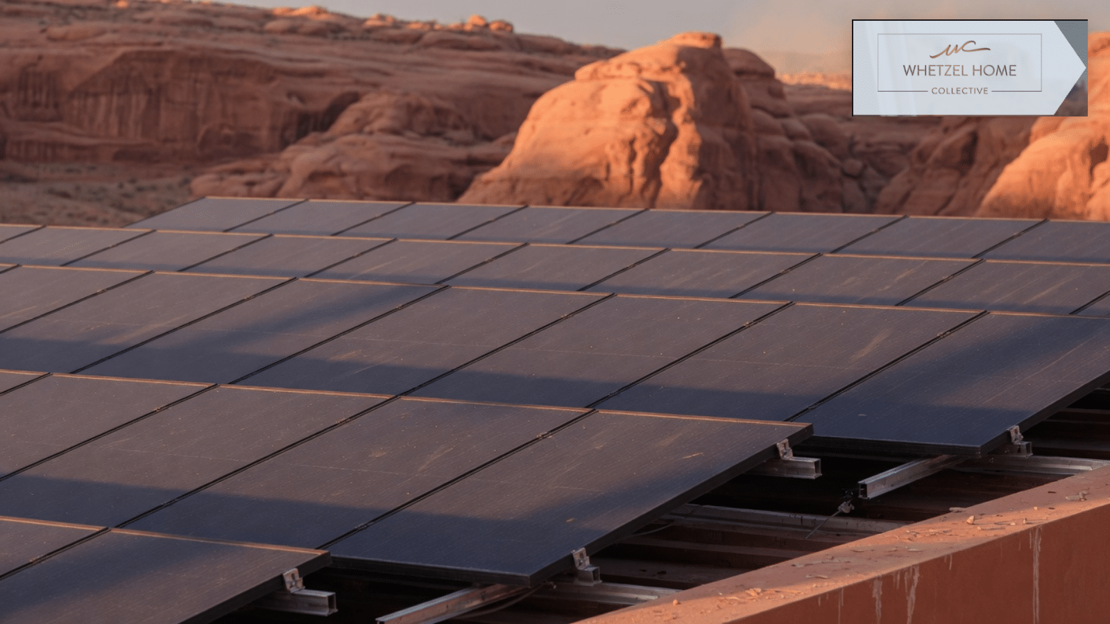 Rooftop solar panels on a desert home with red rock behind them