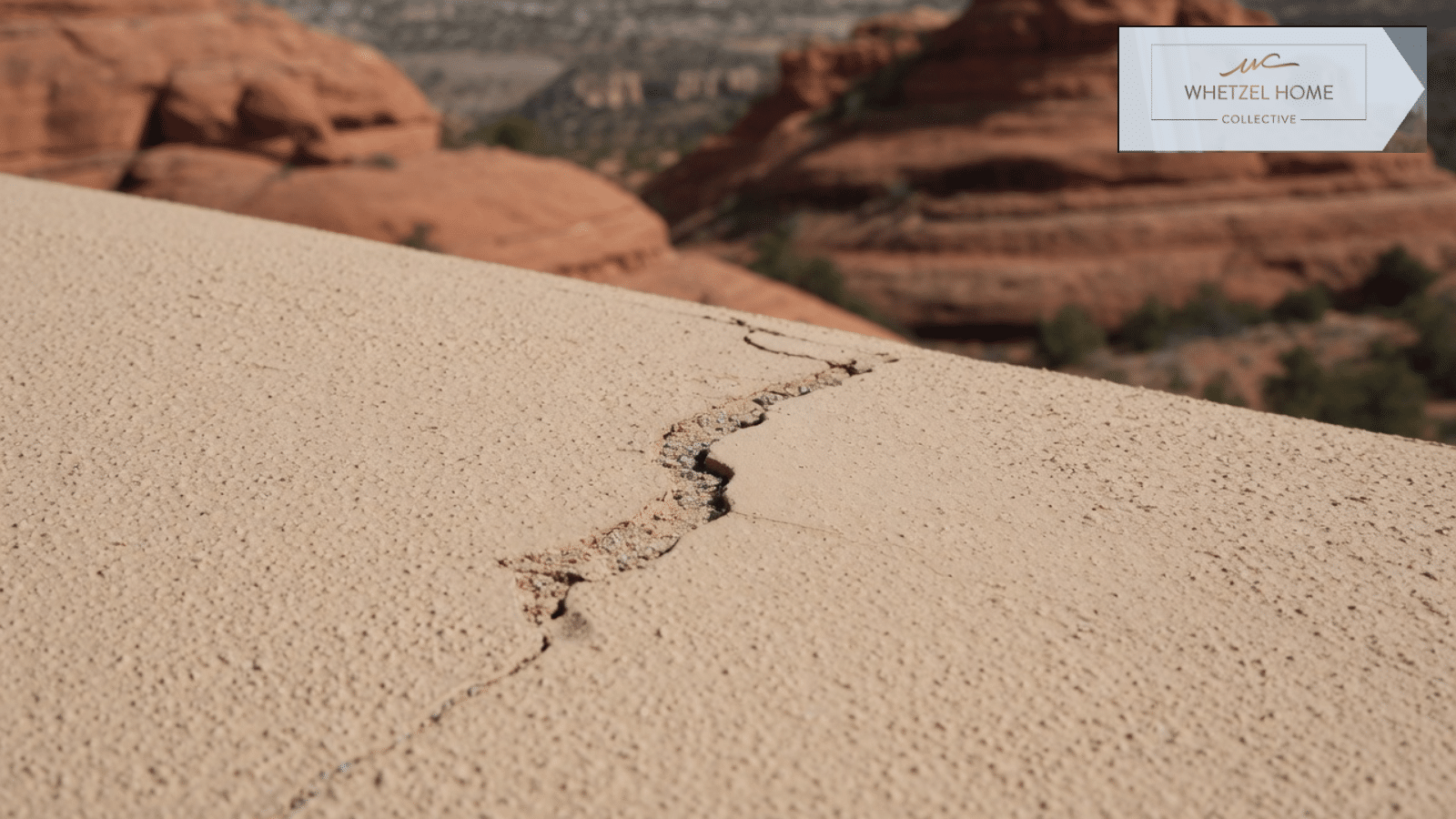 Crack in a stucco surface with red rock hills behind it
