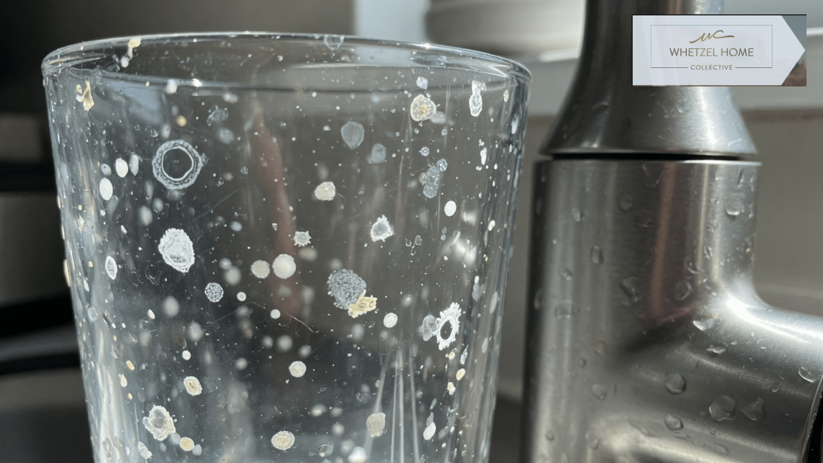 Mineral spots on a drinking glass beside a kitchen faucet