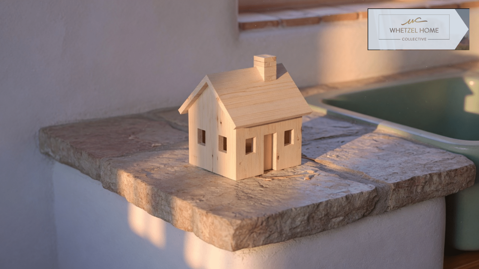 Small wooden house model on a stone counter in warm light